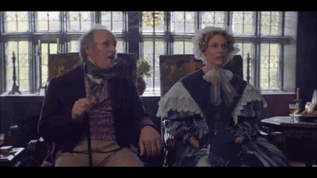 a man with a cane sits next to a woman in a dress