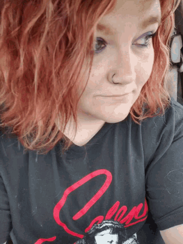 a woman with red hair is wearing a black t-shirt with a red letter o