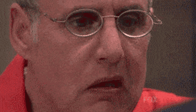 a man in a red shirt is crying with his hands on his face .