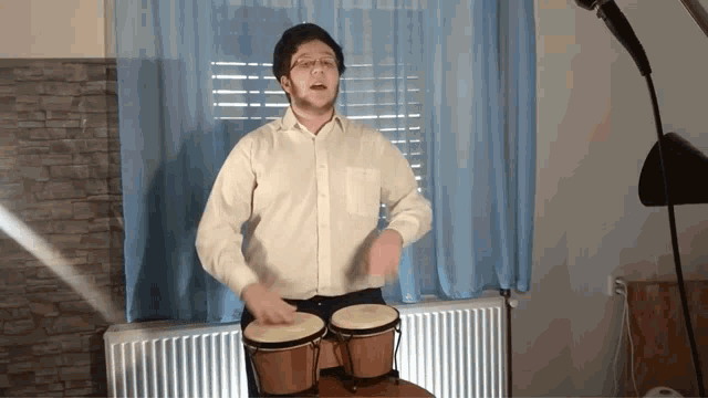 a man in a white shirt is playing bongos