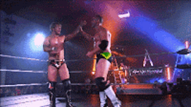 two men are wrestling in a ring and one of them is wearing knee pads