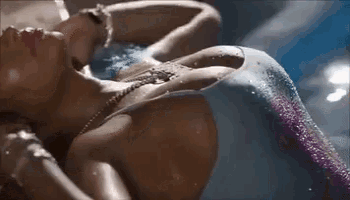 a woman in a mermaid costume is laying in a pool .