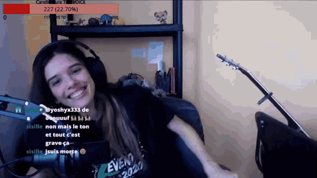 a girl wearing headphones and a shirt that says event 2020 is smiling in front of a microphone
