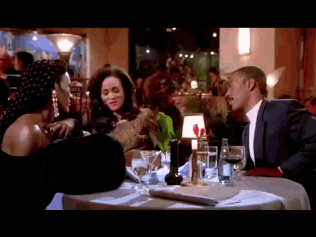 a man in a suit and tie sits at a table with two women