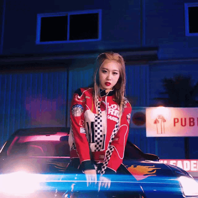 a woman in a race car outfit stands on the hood of a car
