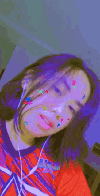 a girl with stars on her face is wearing headphones and making a face