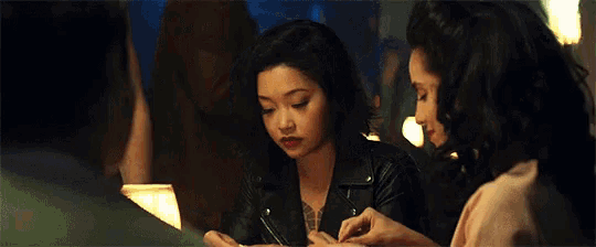 two women are sitting at a table in a dark room eating