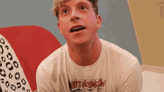 a man wearing a white t-shirt that says " what 's going on "