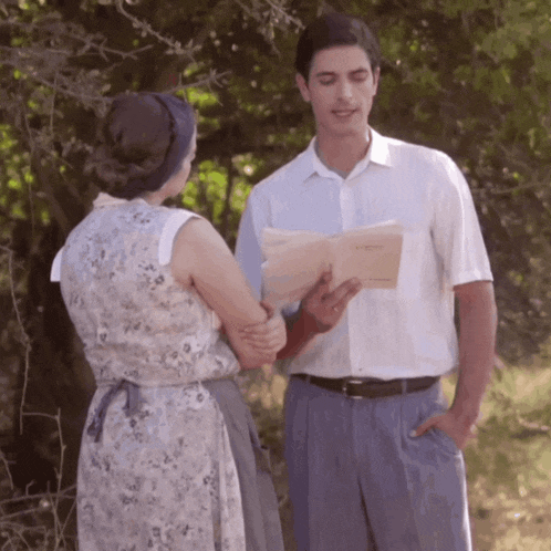 a man and a woman are standing next to each other and the man is holding a book that says " l' amour "