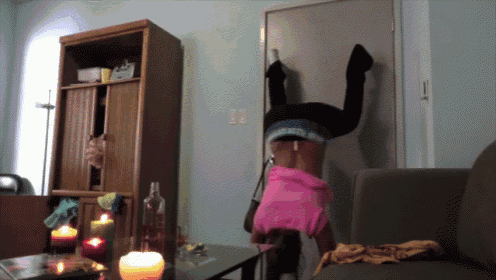 a woman is doing a handstand in a living room with candles on the table