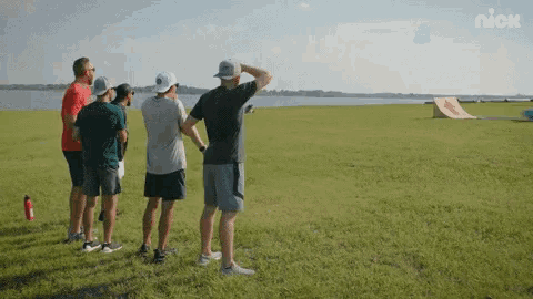 a group of men standing in a grassy field with a nick logo in the background