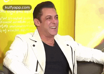 salman khan is wearing a white jacket and a black shirt and smiling .