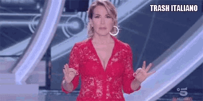 a woman in a red lace dress is standing on a stage with her hands in the air .