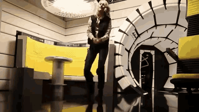 a woman is standing in a room with a yellow couch and a sign that says ' a '
