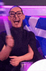 a woman wearing glasses is laughing and holding a piece of paper