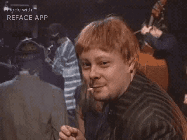 a man with red hair is giving a thumbs up sign while standing in front of a group of people .