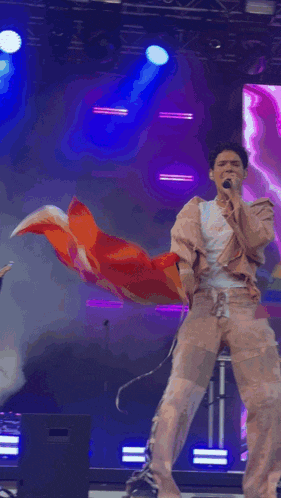 a man singing into a microphone while holding a pink bag