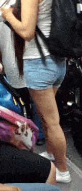 a woman wearing shorts and a white tank top has a backpack on her back