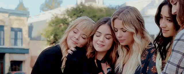 a group of young women are standing next to each other and hugging each other .