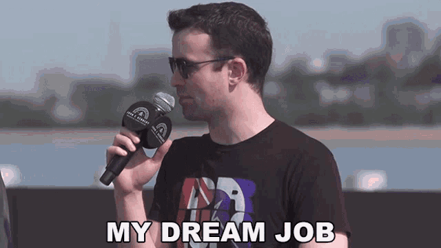a man holding a microphone with the words my dream job below him