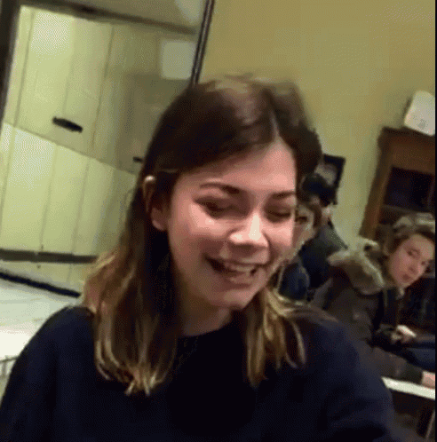 a woman in a black sweater is smiling in a room