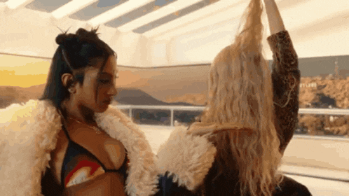 two women are standing next to each other and one of them is wearing a bikini top .