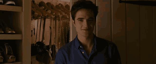 a man in a blue shirt smiles in front of a closet
