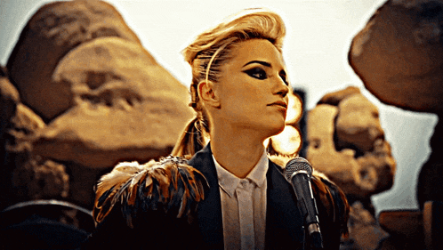 a woman is singing into a microphone in front of a statue