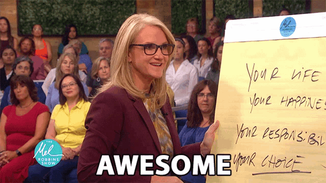 a woman stands in front of a crowd holding a piece of paper that says awesome