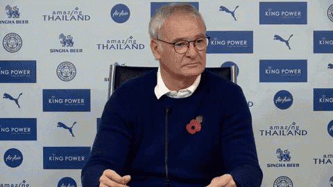 a man sitting in front of a wall with king power logos on it