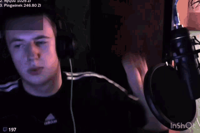 a man wearing headphones and a black adidas shirt is giving a peace sign