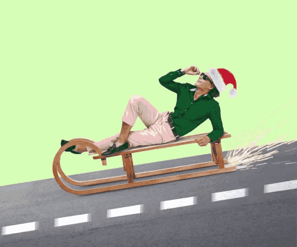 a man wearing a santa hat is laying on a sleigh
