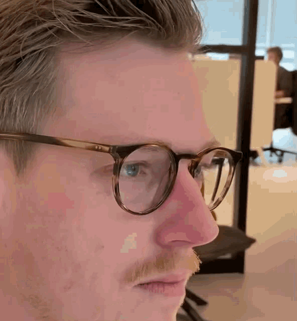 a close up of a man wearing glasses with a red nose
