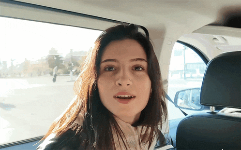 a woman is sitting in the back seat of a car with her mouth open