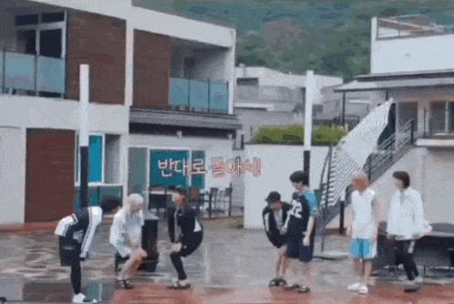 a group of young men are standing in front of a building with korean writing on it