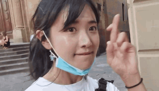 a woman wearing a blue face mask is making a peace sign
