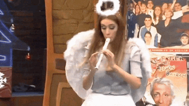 a woman dressed as an angel plays a flute in front of a poster that says ' a tribute to ' on it