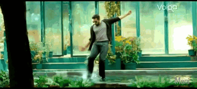 a man is dancing in the rain in front of a greenhouse with volpa written on the screen