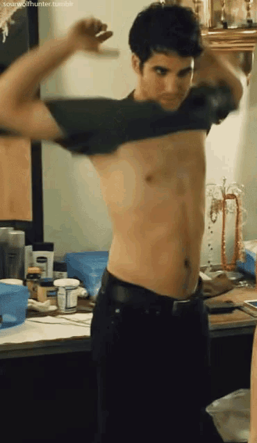 a man without a shirt is standing in front of a counter with a bottle of vaseline on it