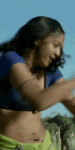 a woman in a blue shirt and green shorts is dancing .