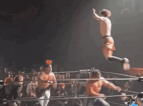 a man is jumping in the air in a wrestling ring with an exit sign behind him