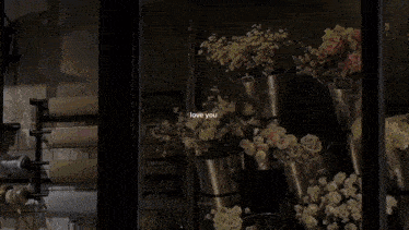 a person is sitting on a balcony surrounded by flowers with the words love you written on the bottom