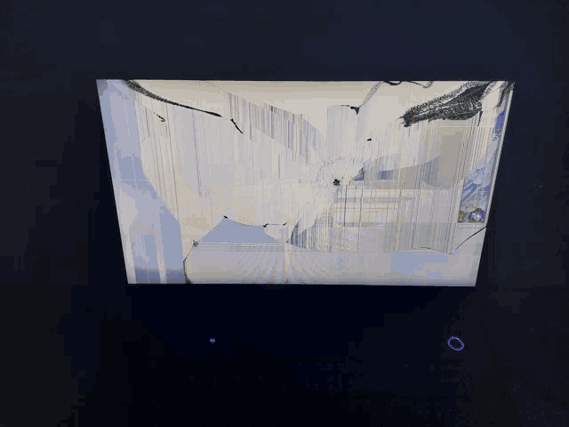 a computer monitor with a broken screen and a blue button