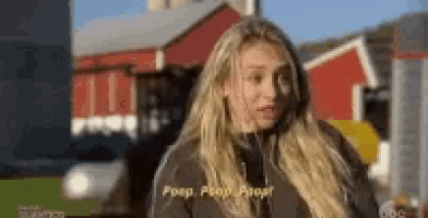 a woman is standing in front of a red barn talking to someone .