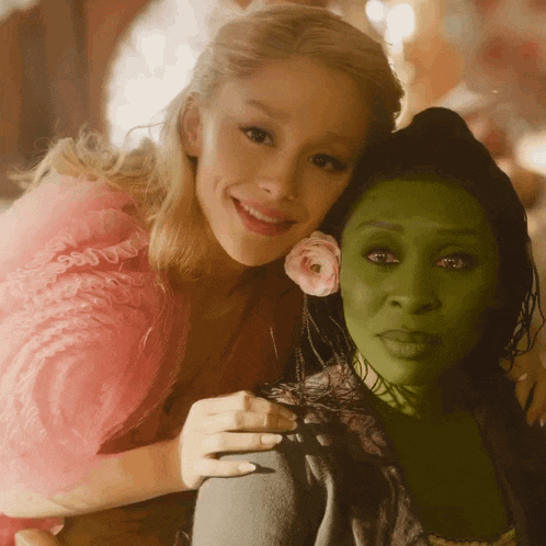 a woman in a pink dress is hugging a woman in a green dress