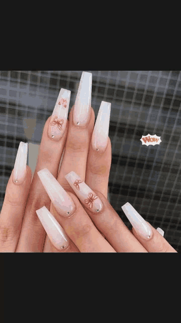 a close up of a woman 's nails with a bow on them .