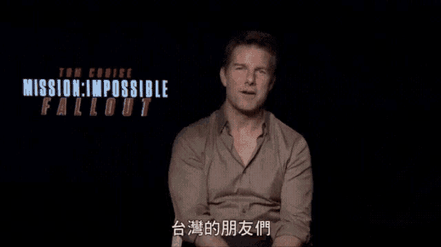 a man is sitting in front of a mission impossible poster