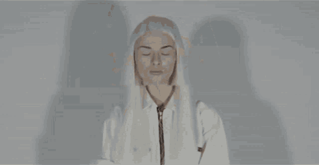 a woman with long white hair is standing with her eyes closed