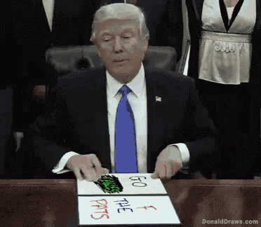 donald trump is sitting at a table with a sign that says i go to the pants