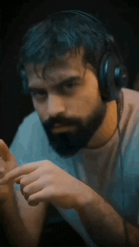 a man with a beard is wearing headphones and looking down